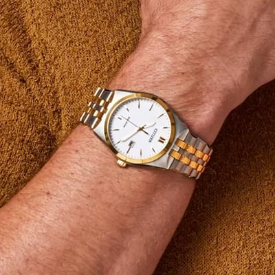 CITIZEN<sup>&reg;</sup> Men's Corso Eco-Drive Stainless Steel Watch - This watch features a gold and silver-tone stainless steel bracelet and case with a 3-hand white dial and date indicator. Other features include luminous hands and gold-tone markers, fold-over clasp closure with hidden push buttons and it's water resistant to 100 meters. Eco-Drive technology, so it is sustainably powered by any light and will never need a battery.